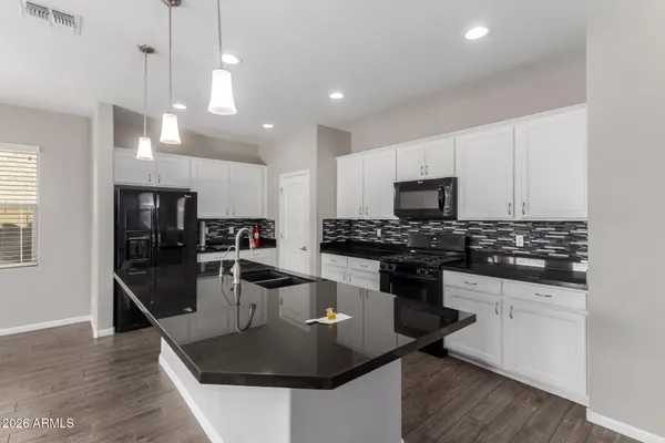 a kitchen with stainless steel appliances granite countertop a sink a stove and a wooden floors