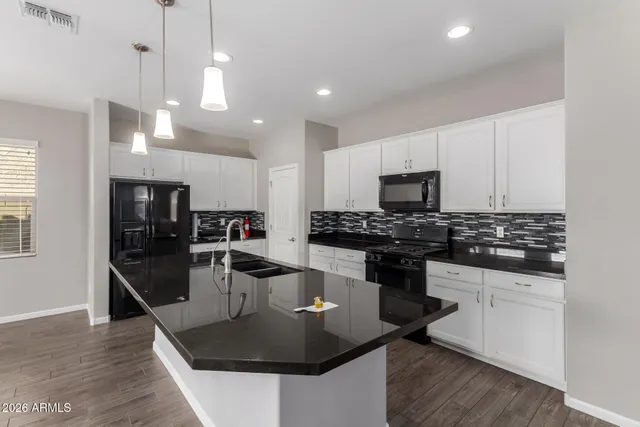 a kitchen with stainless steel appliances granite countertop a sink a stove and a wooden floors