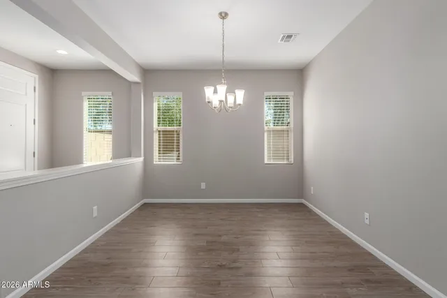 a view of an empty room with wooden floor and windows