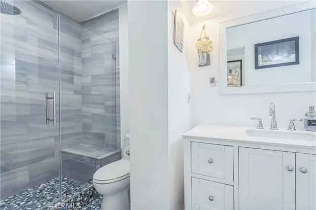 a bathroom with a granite countertop sink a toilet and a shower
