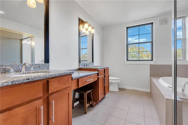 a spacious bathroom with a granite countertop sink toilet and mirror