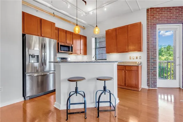 a kitchen with stainless steel appliances granite countertop a refrigerator a stove top oven a sink with island and chairs