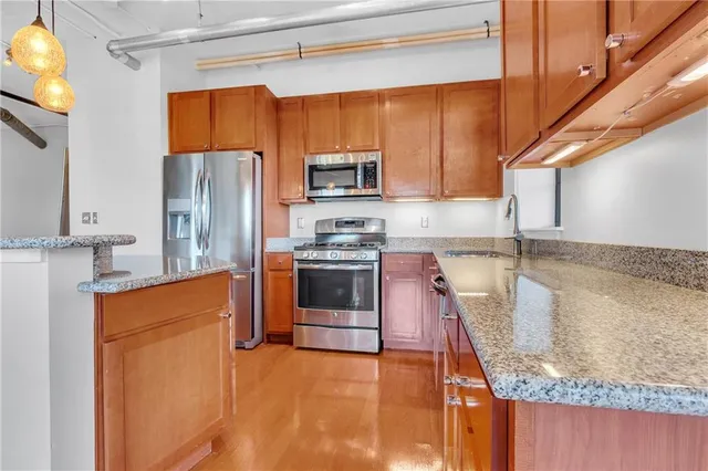 a kitchen with stainless steel appliances granite countertop a sink a stove and a refrigerator