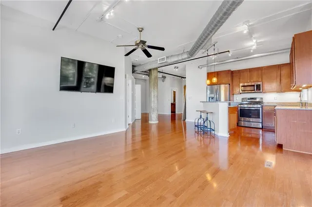 a view of a livingroom with furniture a ceiling fan and wooden floor