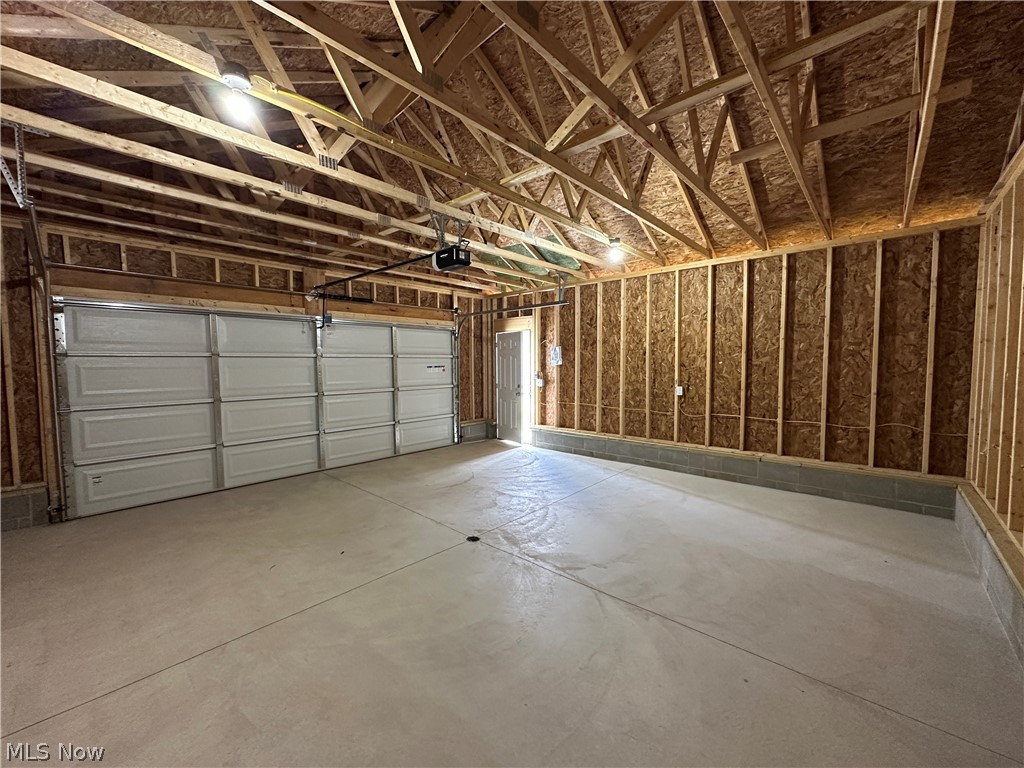 78 Prospect Street Struthers, OH 44471 - Photo 17 of 17 Spacious garage featuring a concrete floor, exposed wood framing, and a panel garage door with an automatic opener