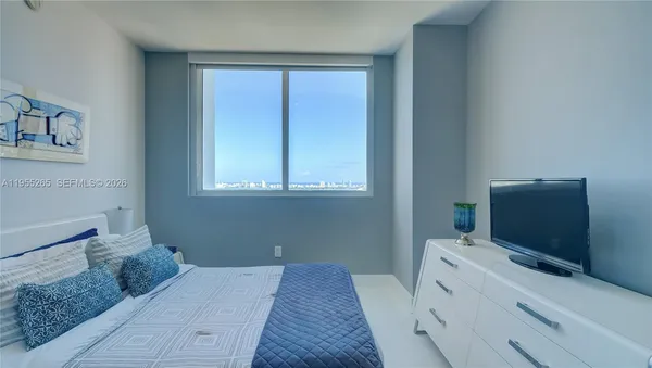 a bedroom with a bed and flat tv screen on the dresser