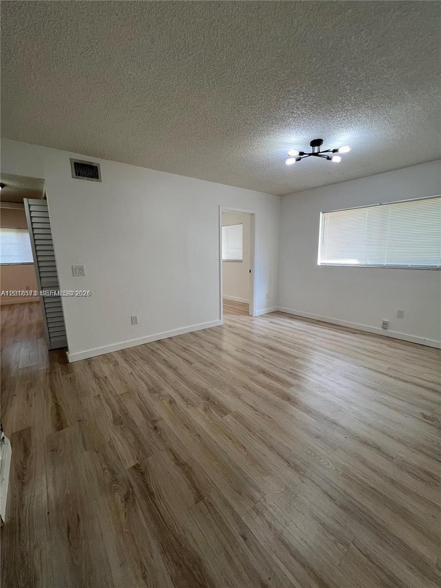 3700 North 56th Avenue, Unit 1012 Hollywood, FL 33021 - Photo 6 of 11 an empty room with wooden floor and windows