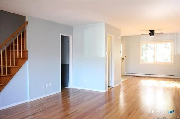 a view of an empty room with wooden floor and a window
