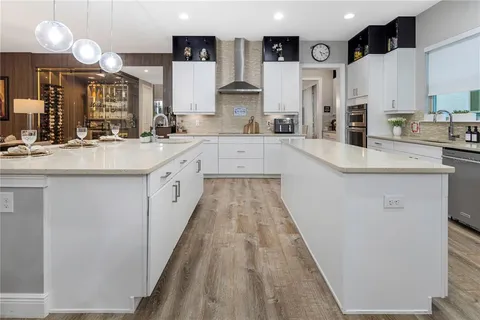 a large white kitchen with a white countertops a dining table and chairs with wooden floor