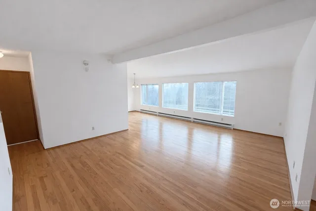 an empty room with wooden floor and windows