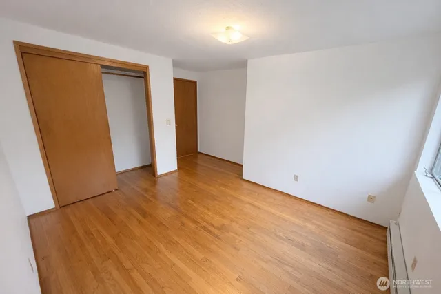 an empty room with wooden floor and closet
