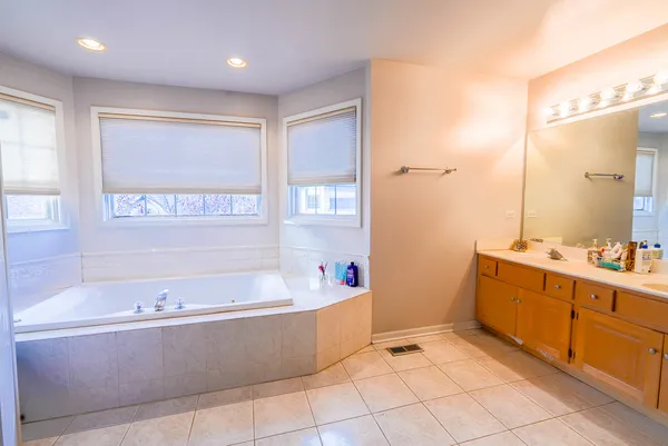 a spacious bathroom with a tub sink and mirror