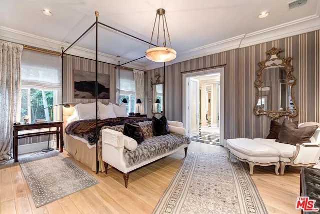 a bedroom with a bed a chandelier and a flat tv screen