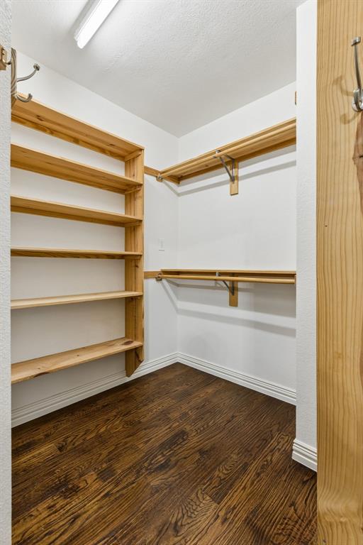 2925 Sunset Ridge McKinney, TX 75072 - Photo 24 of 33 Additional primary custom walk-in closet complete with built-in wood shelving, extensive storage solutions, and rich hardwood flooring, providing exceptional organization and functionality.