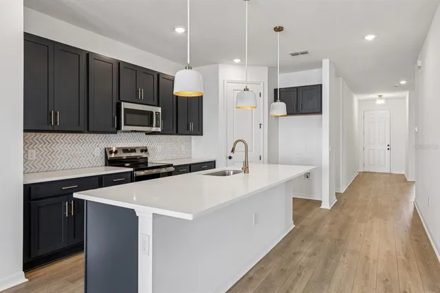 a kitchen with stainless steel appliances a sink a stove a refrigerator and cabinets