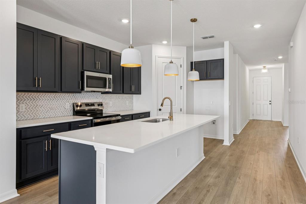 5721 Haystack Drive St. Cloud, FL 34771 - Photo 7 of 36 a kitchen with stainless steel appliances a sink a stove a refrigerator and cabinets