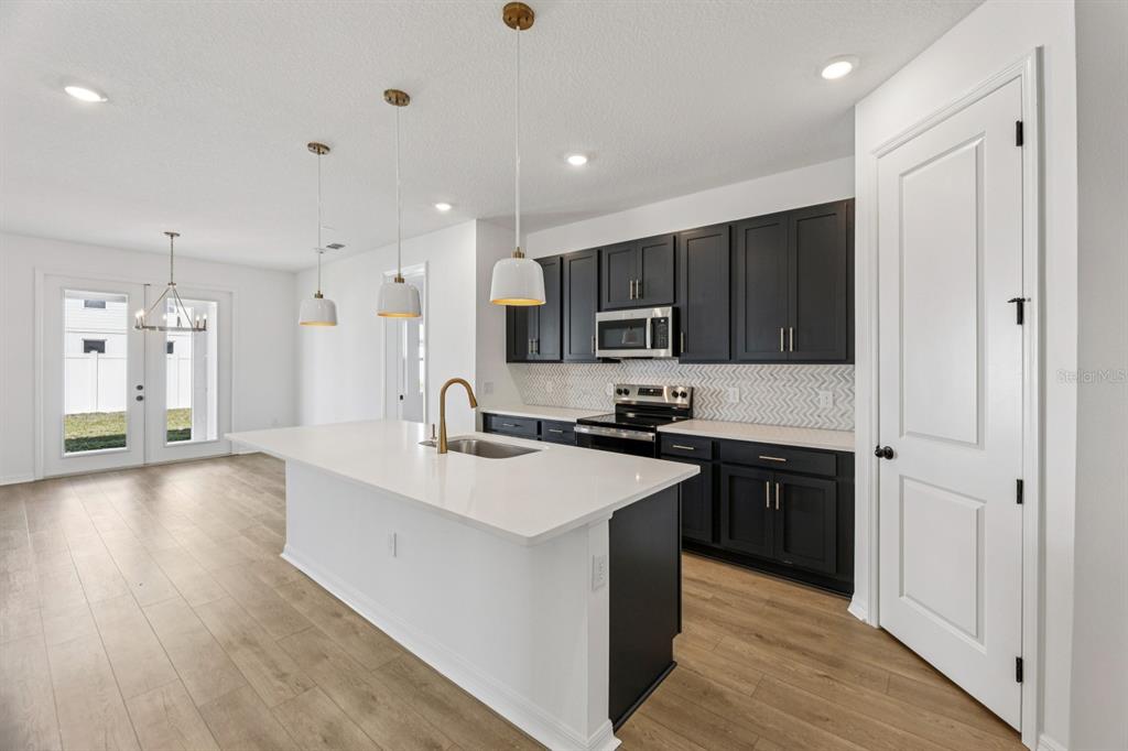5721 Haystack Drive St. Cloud, FL 34771 - Photo 8 of 36 a large kitchen with stainless steel appliances granite countertop a sink stove and refrigerator