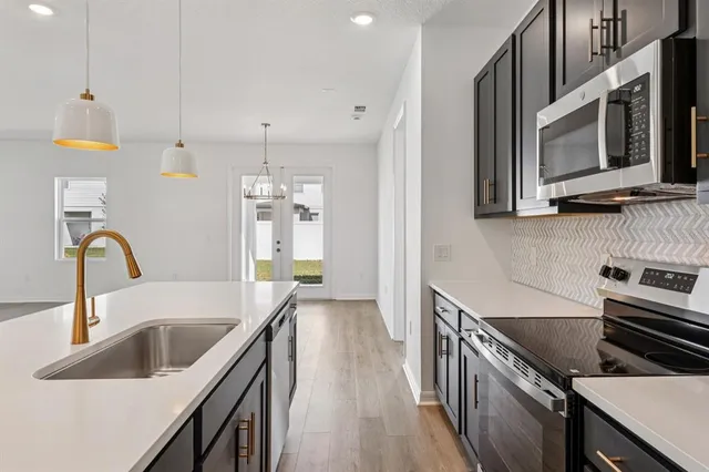 a kitchen with stainless steel appliances a sink a stove top oven a counter space and cabinets