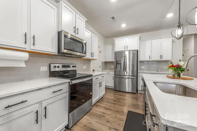 a kitchen with stainless steel appliances granite countertop a refrigerator a sink a stove a microwave and wooden cabinets