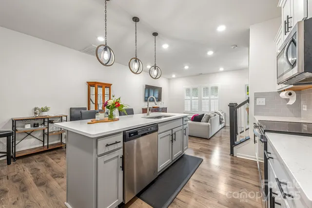 a large kitchen with stainless steel appliances a stove a sink dishwasher and a fireplace with wooden floor