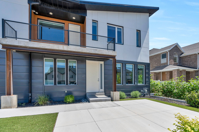 7045 South 300 East Midvale, UT 84047 - Photo 10 of 49 Modern exterior featuring a prominent second-story balcony with metal railing, a white entry door, and a concrete driveway