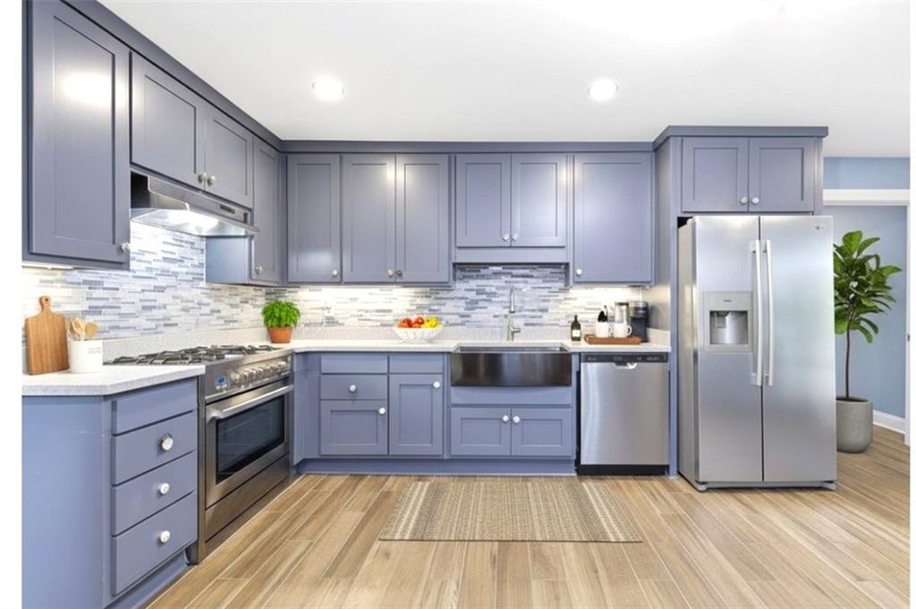a kitchen with stainless steel appliances granite countertop a stove a sink dishwasher a refrigerator and cabinets with wooden floor