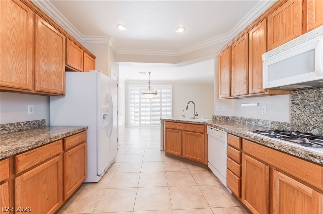 10481 Riverside Park Avenue Las Vegas, NV 89135 - Photo 15 of 51 Kitchen featuring ornamental molding, a peninsula, white appliances, light tile patterned flooring, and decorative light fixtures