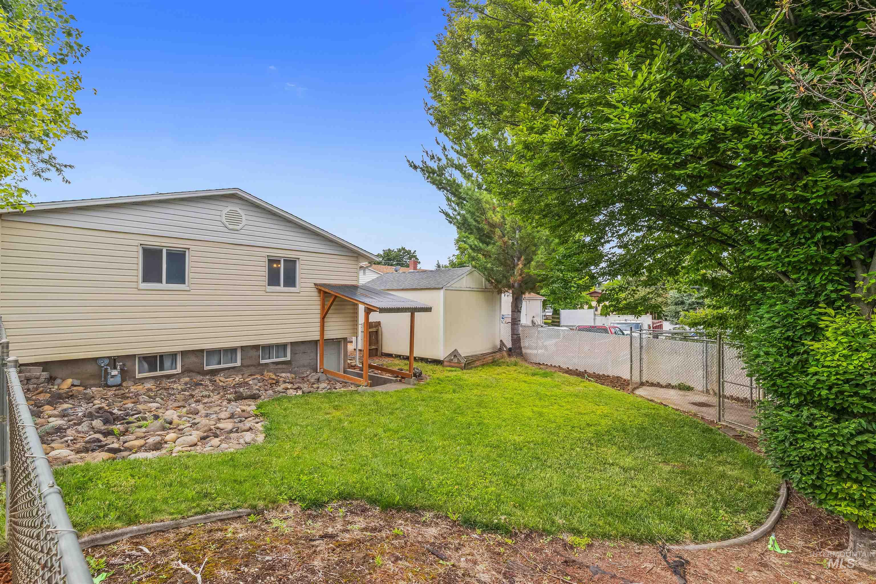 3620 18th Street Lewiston, ID 83501 - Photo 31 of 32 Expansive green lawn with mature trees and a chain-link fence
