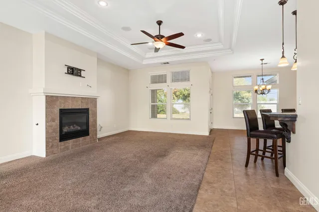 a view of a livingroom with a fireplace a ceiling fan and windows