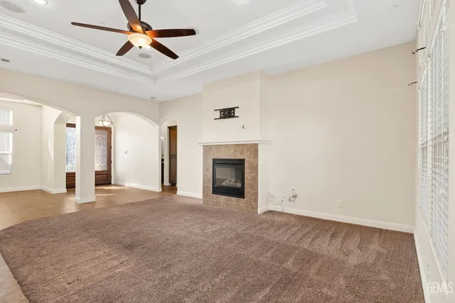 a view of a livingroom with a chandelier fan and kitchen view