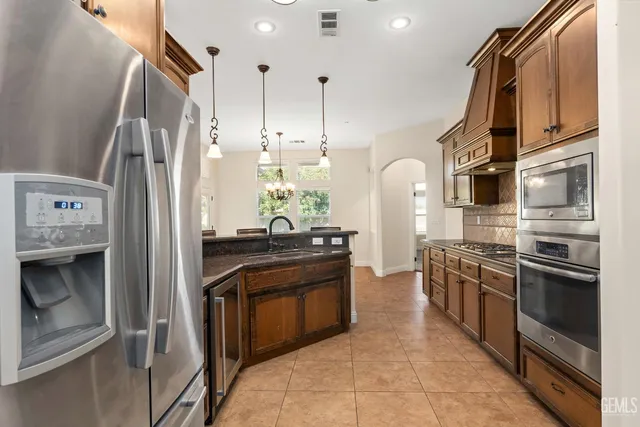 a kitchen with stainless steel appliances granite countertop a sink a stove and a wooden floors