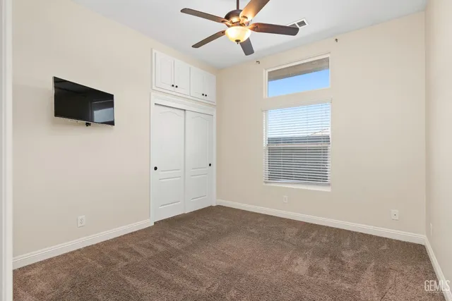 an empty room with ceiling fan and window