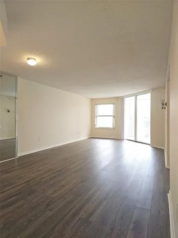 a view of an empty room with wooden floor and window