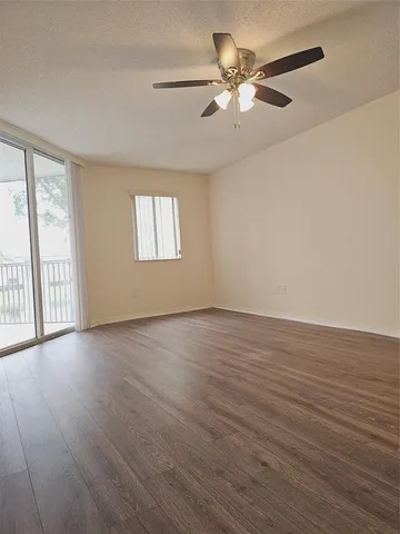an empty room with wooden floor fan and windows