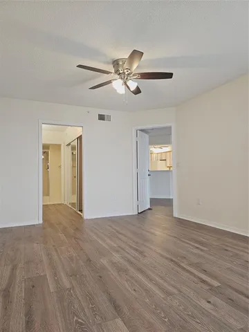 a view of an empty room with window and wooden floor