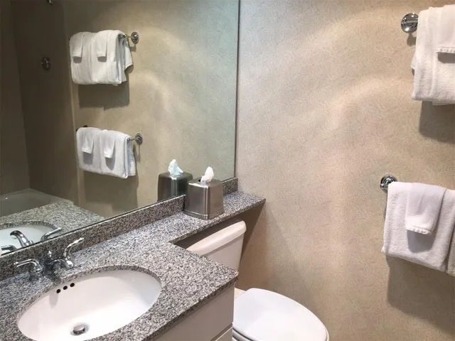 a bathroom with a granite countertop toilet sink and mirror