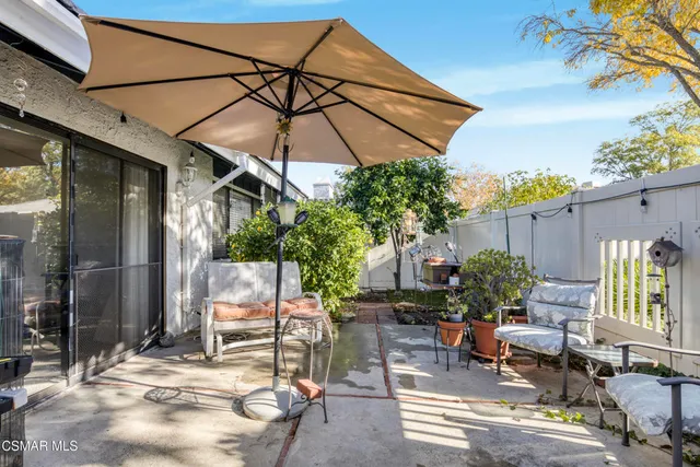 a patio with a table and chairs under an umbrella