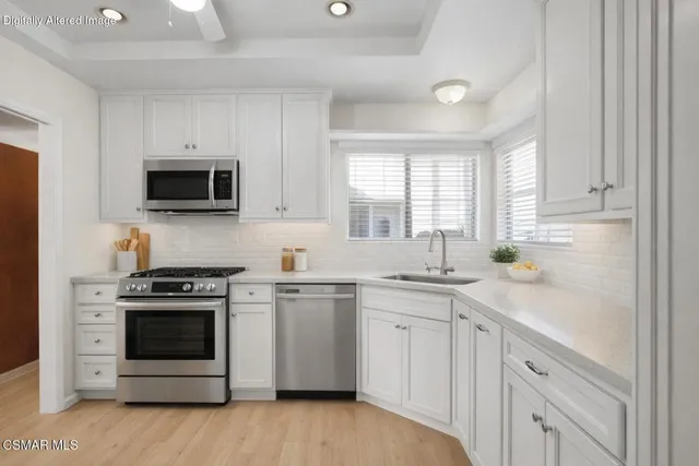 a kitchen with white cabinets stainless steel appliances and sink