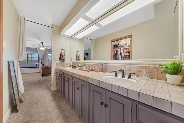 a bathroom with a granite countertop sink a toilet a mirror and shower