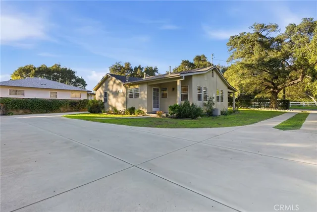 a view of a house with a yard and large trees