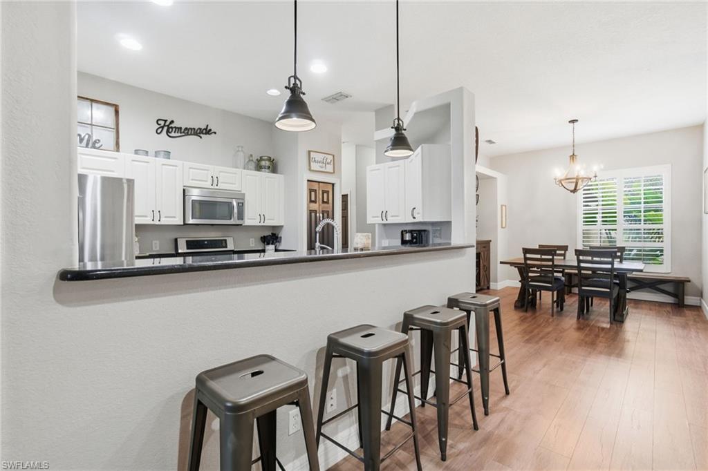 2900 Orange Grove Trail Naples, FL 34120 - Photo 9 of 46 a open kitchen with stainless steel appliances granite countertop a stove a sink a dining table and chairs with wooden floor