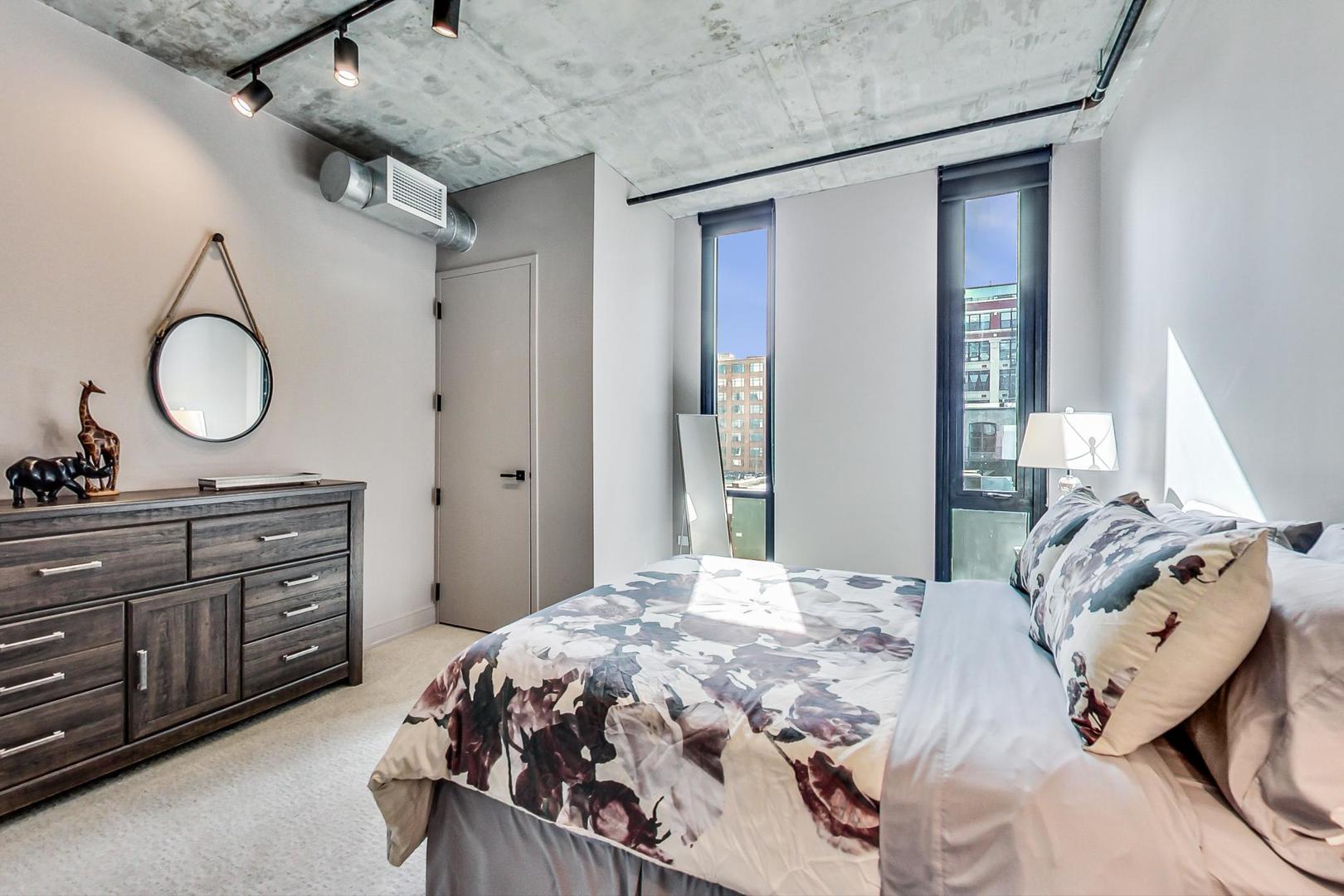 111 South Peoria Street, Unit 309 Chicago, IL 60607 - Photo 30 of 43 a bedroom with a bed and large mirror