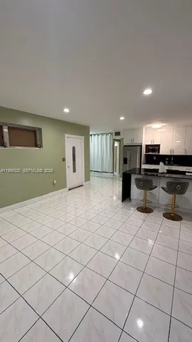 a large white kitchen with stainless steel appliances kitchen island granite countertop a refrigerator a stove and a sink