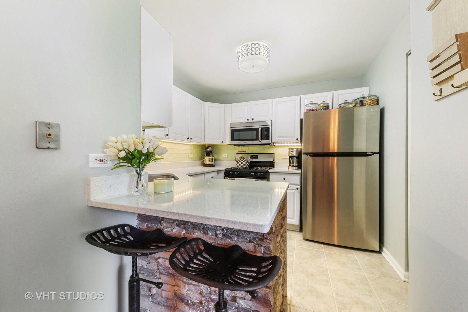 471 River Bend Road, Unit 103 Naperville, IL 60540 - Photo 7 of 29 a kitchen with stainless steel appliances a refrigerator a stove a sink dishwasher and white countertops with wooden floor