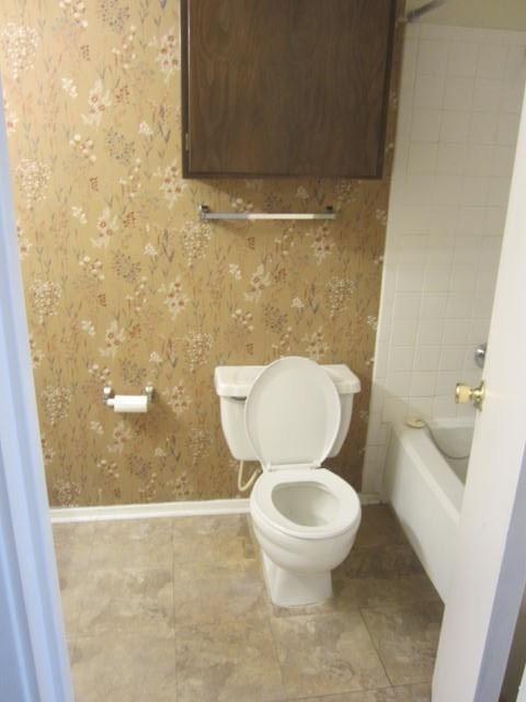 12480 Abrams Road, Unit 521 Dallas, TX 75243 - Photo 8 of 26 Bathroom featuring a wood-finish overhead cabinet, white toilet, and tub with white tile surround
