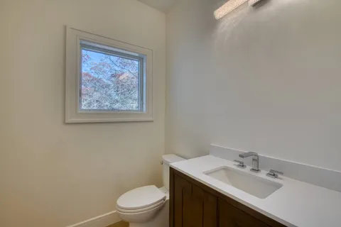 a bathroom with a granite countertop toilet a sink and mirror