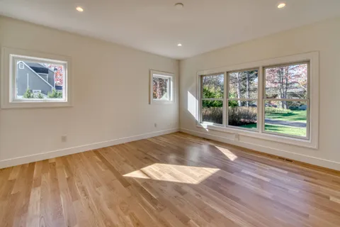 a view of empty room with wooden floor and fan