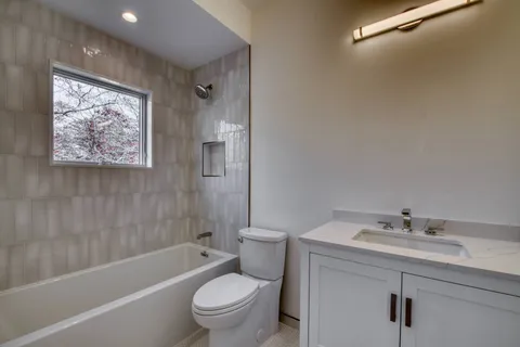 a bathroom with a bathtub shower sink mirror vanity and toilet