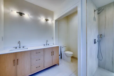 a bathroom with a double vanity sink toilet and shower