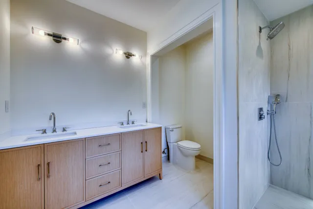 a bathroom with a double vanity sink toilet and shower